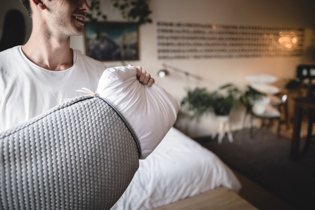 man pulls gray pillow case from white pillow