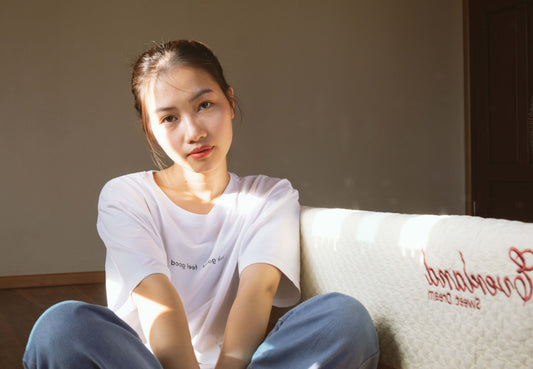a woman sitting on a couch with a mattress behind her