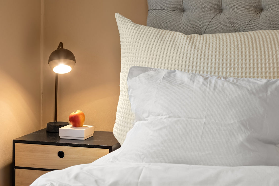 A bed with a white comforter and a night stand