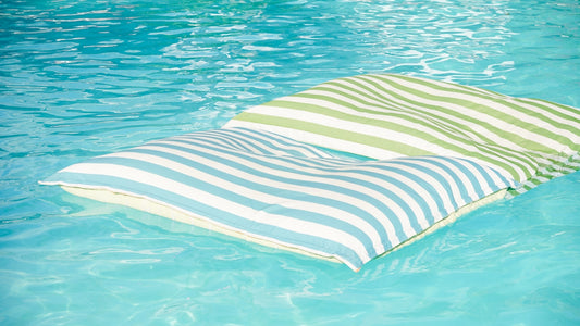 Two striped cushions floating on clear blue water